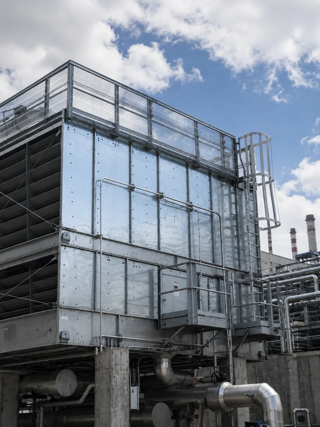 Industrial cooling tower with louvred air inlet, service ladder and circulation pipework